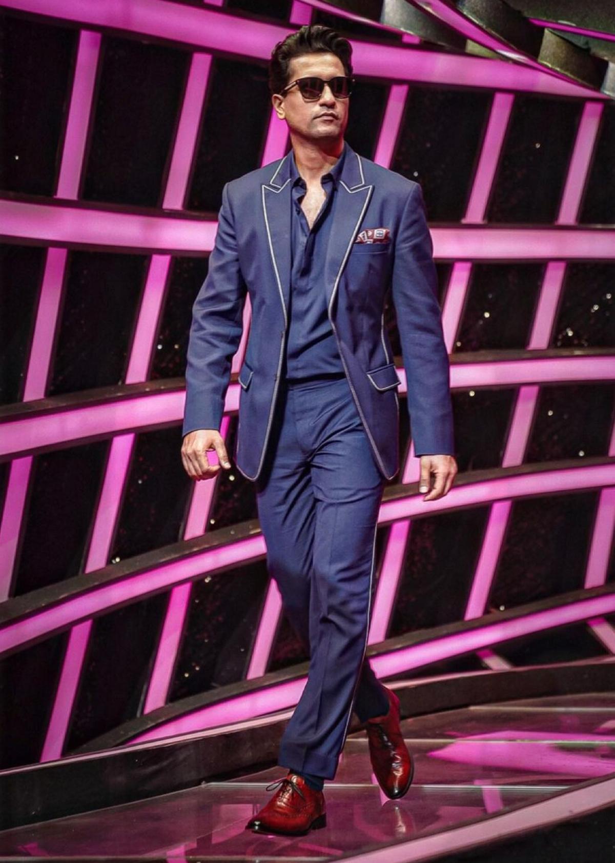 Here is Vicky Kaushal looking all dapper in his dark blue blazer with matching pants. The white outline on the lapels and pockets of the blazer, along with the sides of his bottoms, gave a playful touch to his otherwise formal attire. To complete the look, Vicky chose brown leather shoes. With black sunglasses on, Mr. Kaushal simply slayed all the way with his chic blue ensemble. P.S. We can't get our eyes off his chiselled and clean-shaved face, what about you?   
